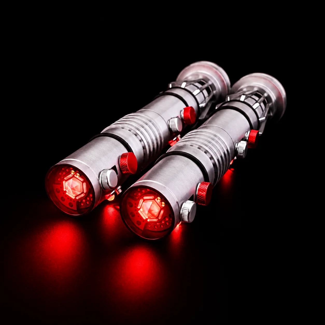 Two Maul hilts floating above a black surface with illuminated red internal cores
